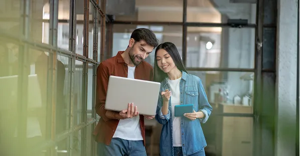 Two colleagues walking with a laptop in an office