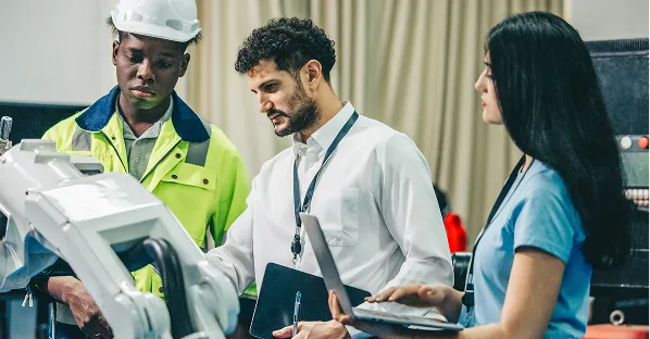 Workers in hi-vis reviewing equipment with a tablet