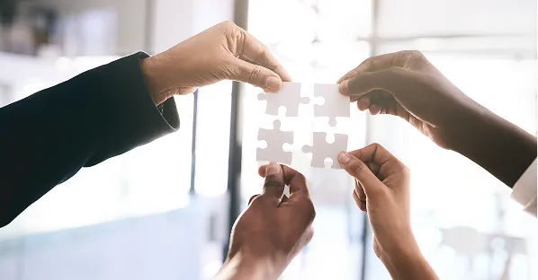 Hands joining puzzle pieces