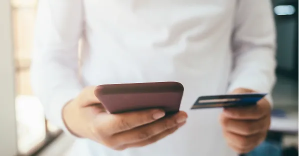 Person holding a phone and card to pay