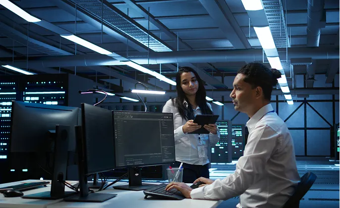IT staff working at computers in a server room