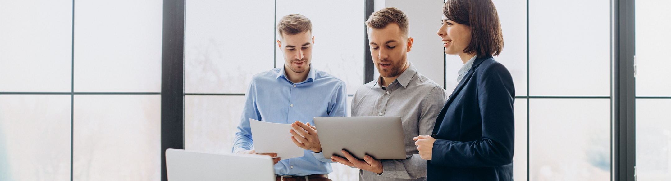 Three colleagues reviewing a laptop in an office