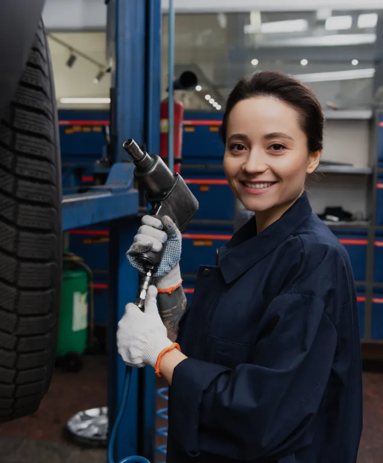 Smiling mechanic holding an impact wrench by tyres
