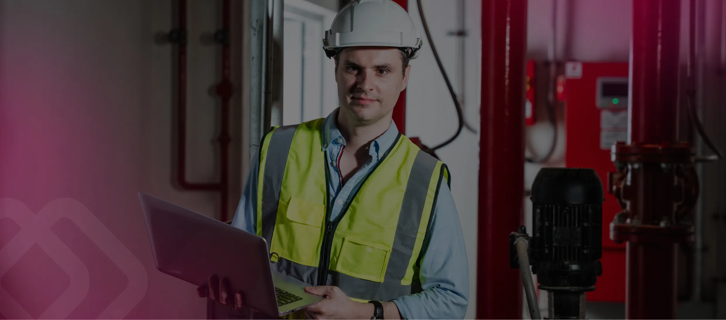 Worker in hi-vis using a laptop by equipment