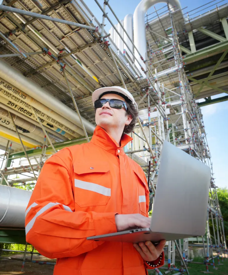 Worker in coveralls using a laptop on a site