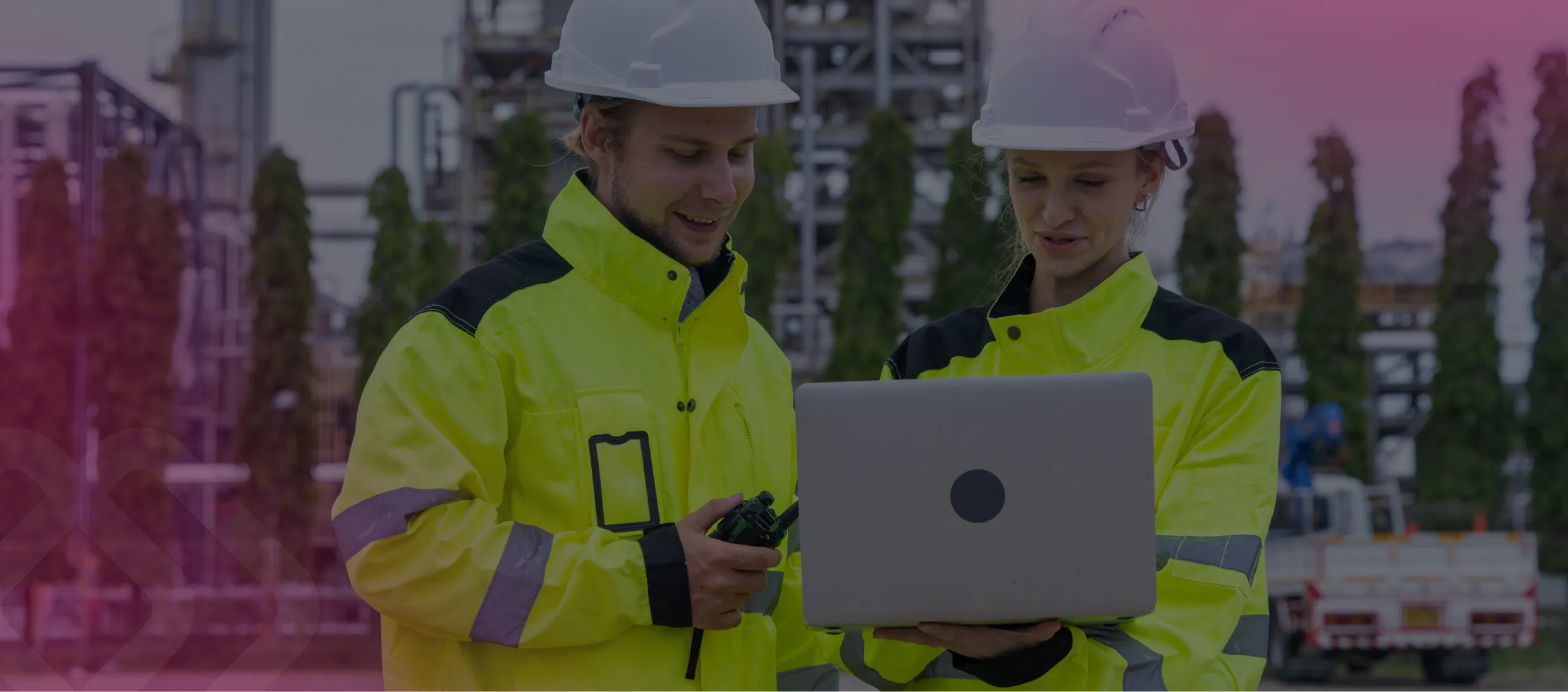 Two workers in hi-vis using a laptop
