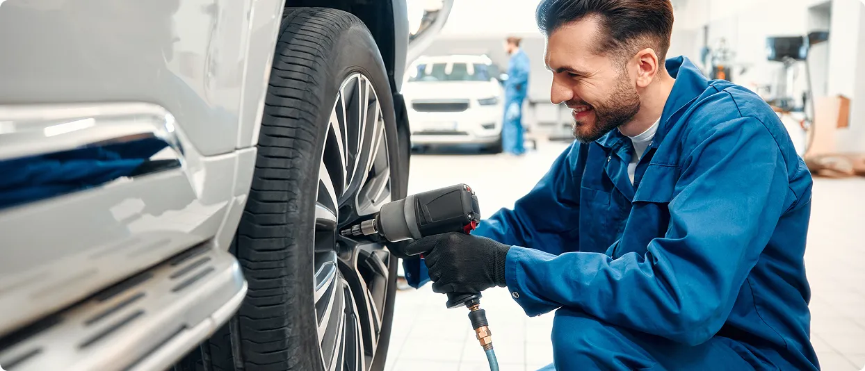 Mechanic using an impact wrench on a car wheel