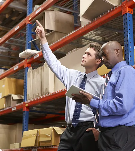 Two colleagues checking high warehouse shelves with a tablet