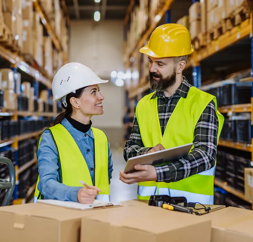 Two warehouse workers in hi-vis checking stock with a tablet