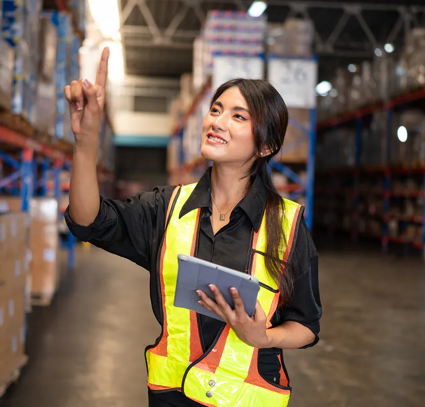 Warehouse worker in hi-vis checking shelves with a tablet