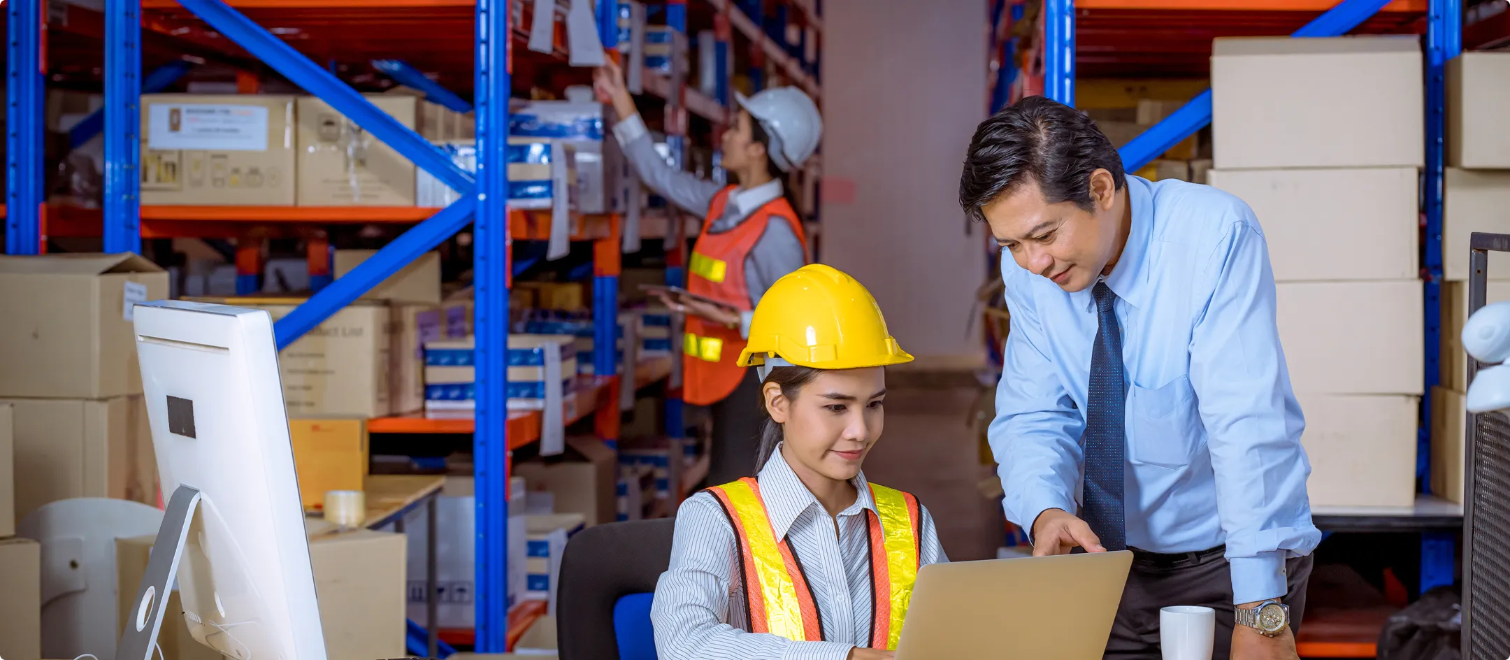 Workers in hi-vis at a computer in a warehouse