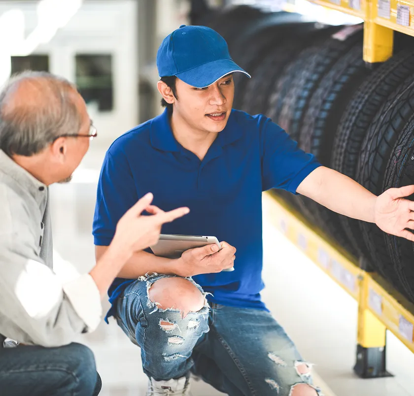 Salesperson showing tyres to a customer using a tablet
