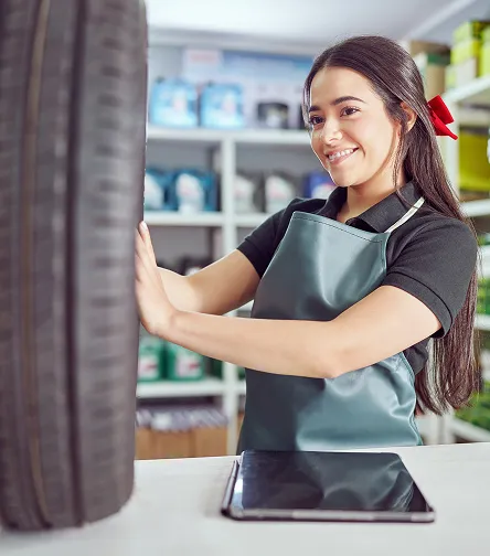 Smiling shop worker with a tire and tablet