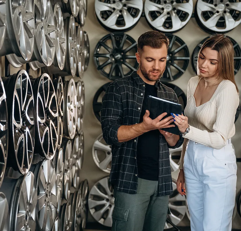 Customers viewing wheel options on a tablet in front of a wheel display