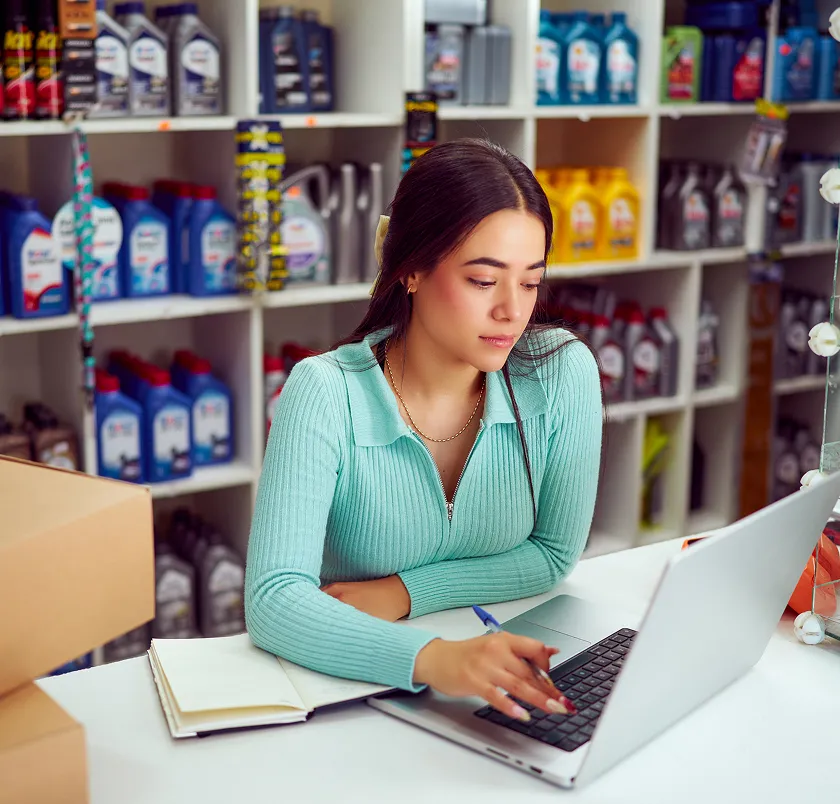 Woman taking notes with a laptop in a retail stockroom