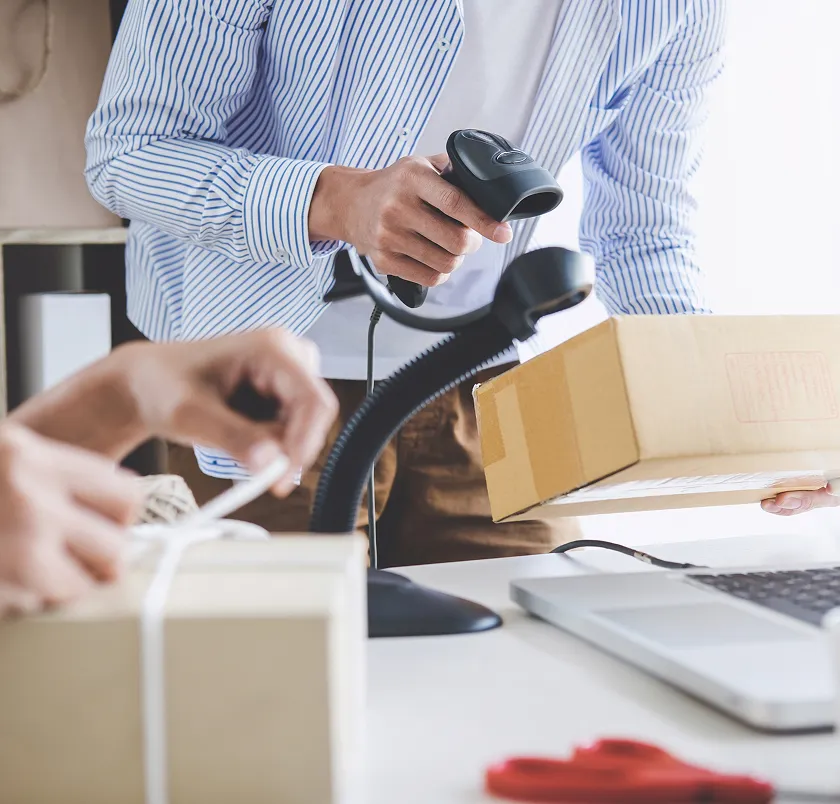 Person scanning a parcel with a barcode scanner while packing