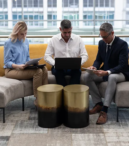 Three colleagues reviewing a laptop on an office sofa