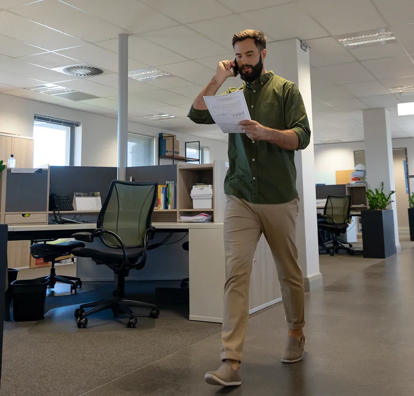 Man walking through an office while talking on the phone