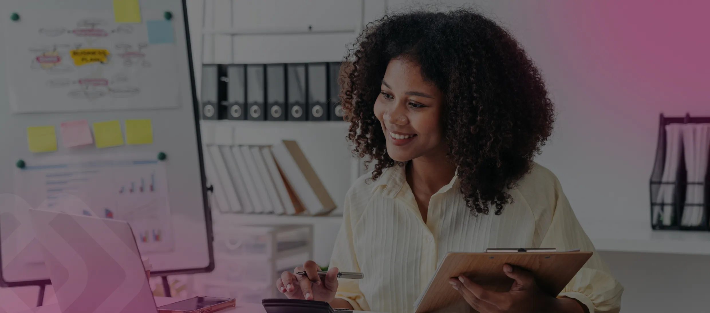 Woman smiling at a laptop by a whiteboard