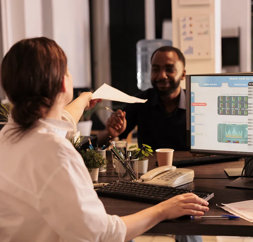 Colleagues reviewing data on a monitor at an office desk