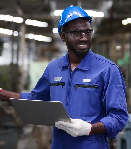 Smiling worker in overalls holding a laptop