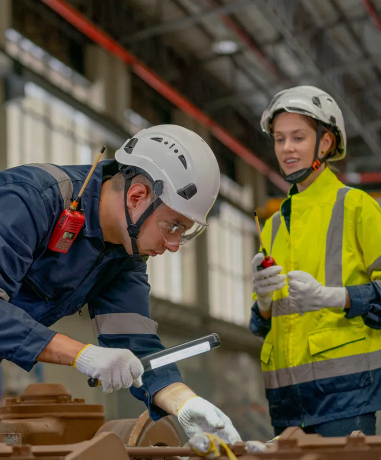 Two workers inspecting a component with a torch