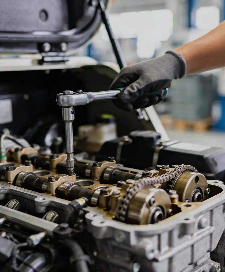 Close-up of a gloved hand using a wrench on an engine