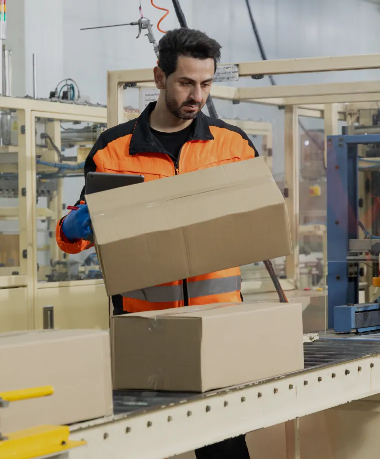 Warehouse worker packing a cardboard box on a conveyor line
