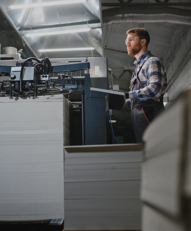 Worker beside industrial printing machinery