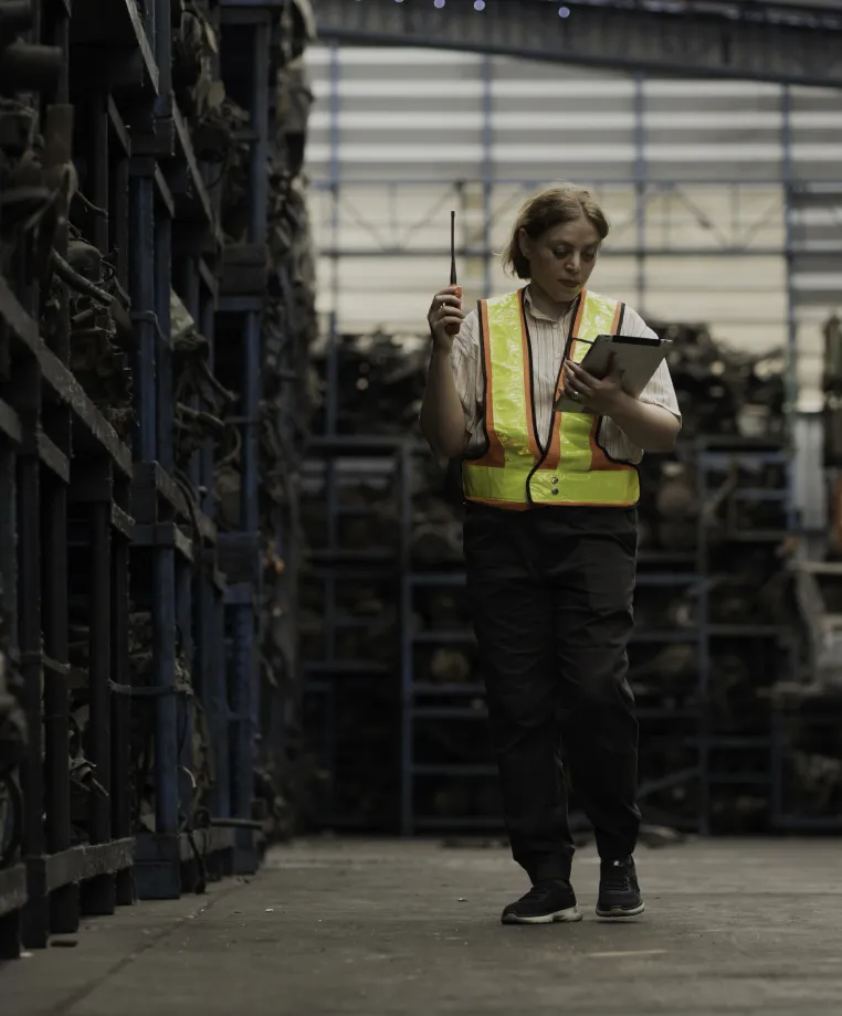 Worker in a hi-vis vest using a tablet in a warehouse storage aisle