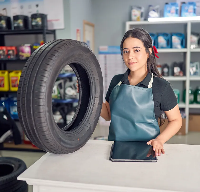 Shop assistant standing at a tyre retailer counter with a tyre