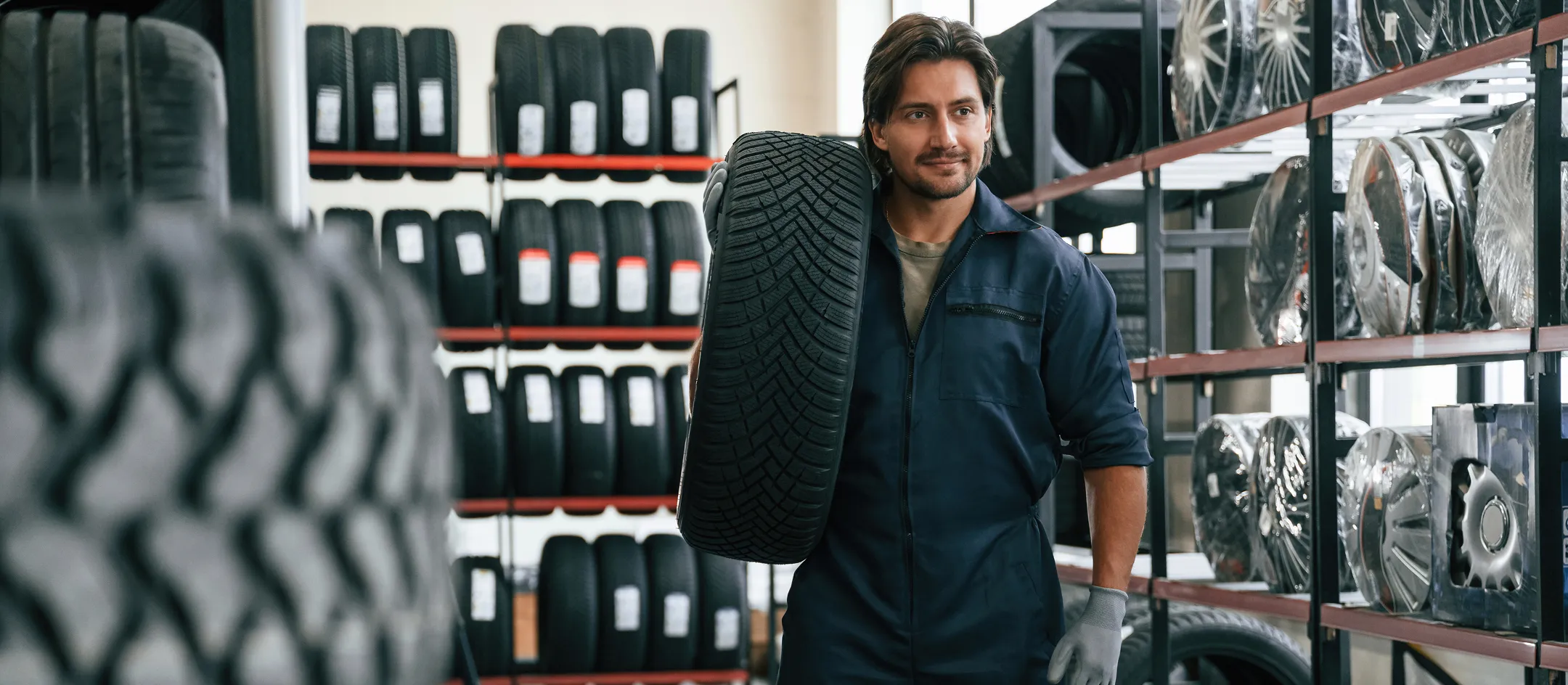 Worker carrying a tyre in a tyre warehouse