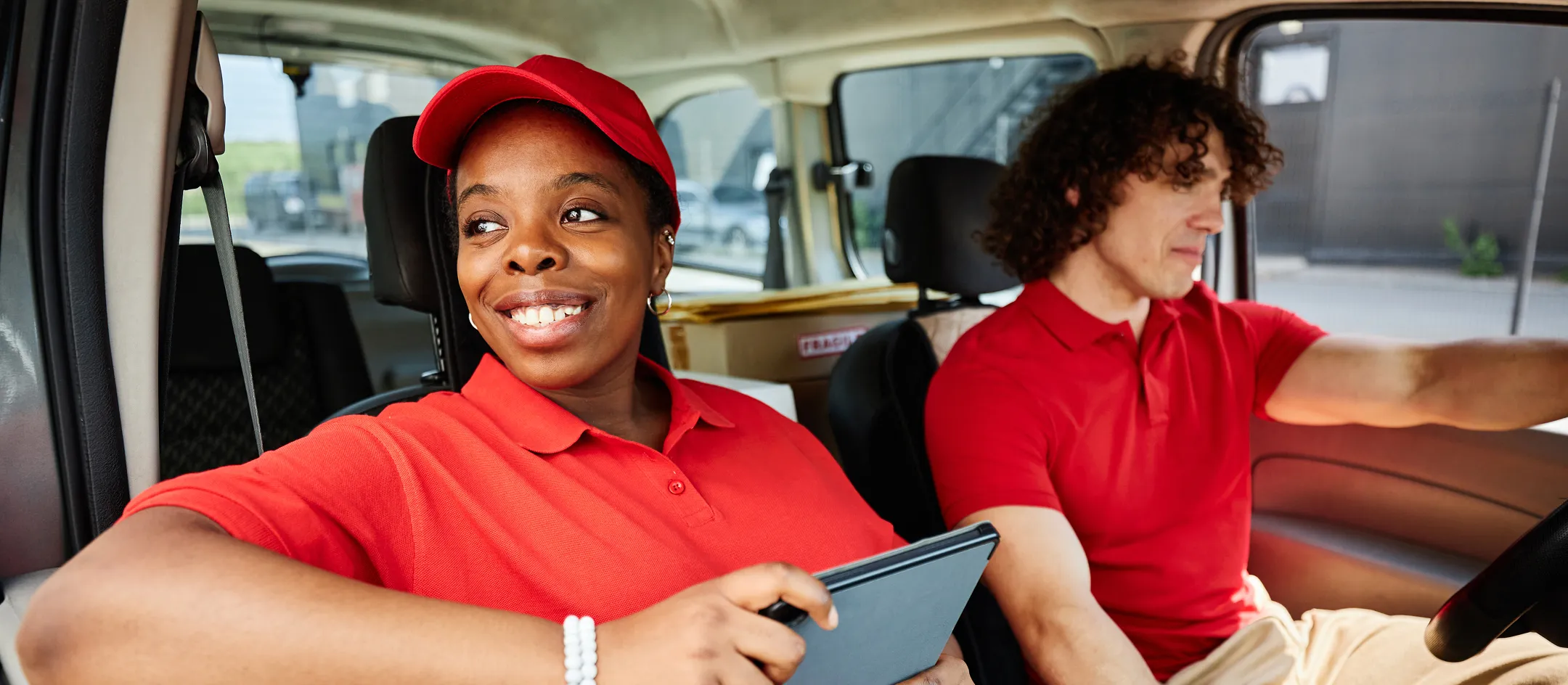 Two delivery drivers using a tablet in a van cab
