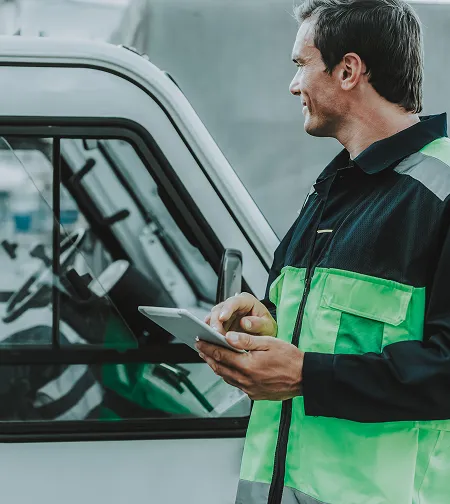 Operator in an excavator cab holding a tablet