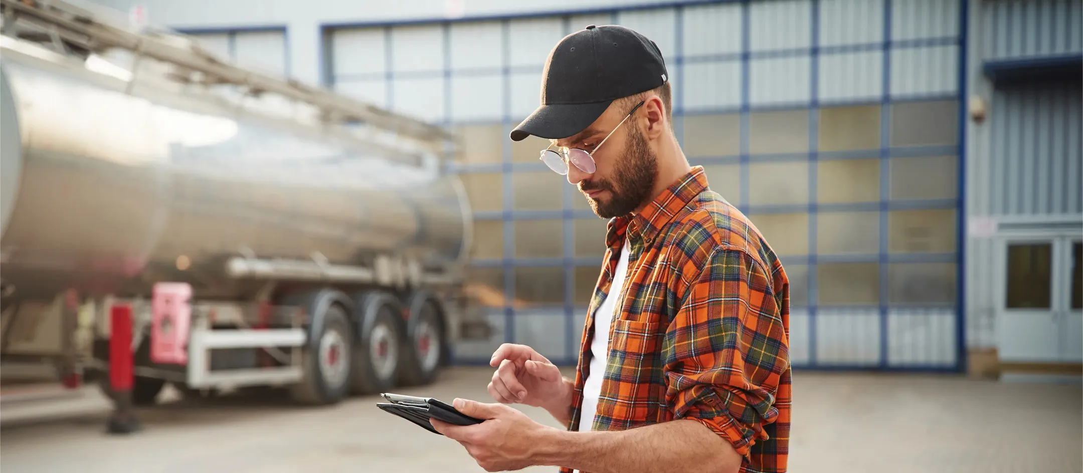 Worker checking a mobile device beside a tanker truck