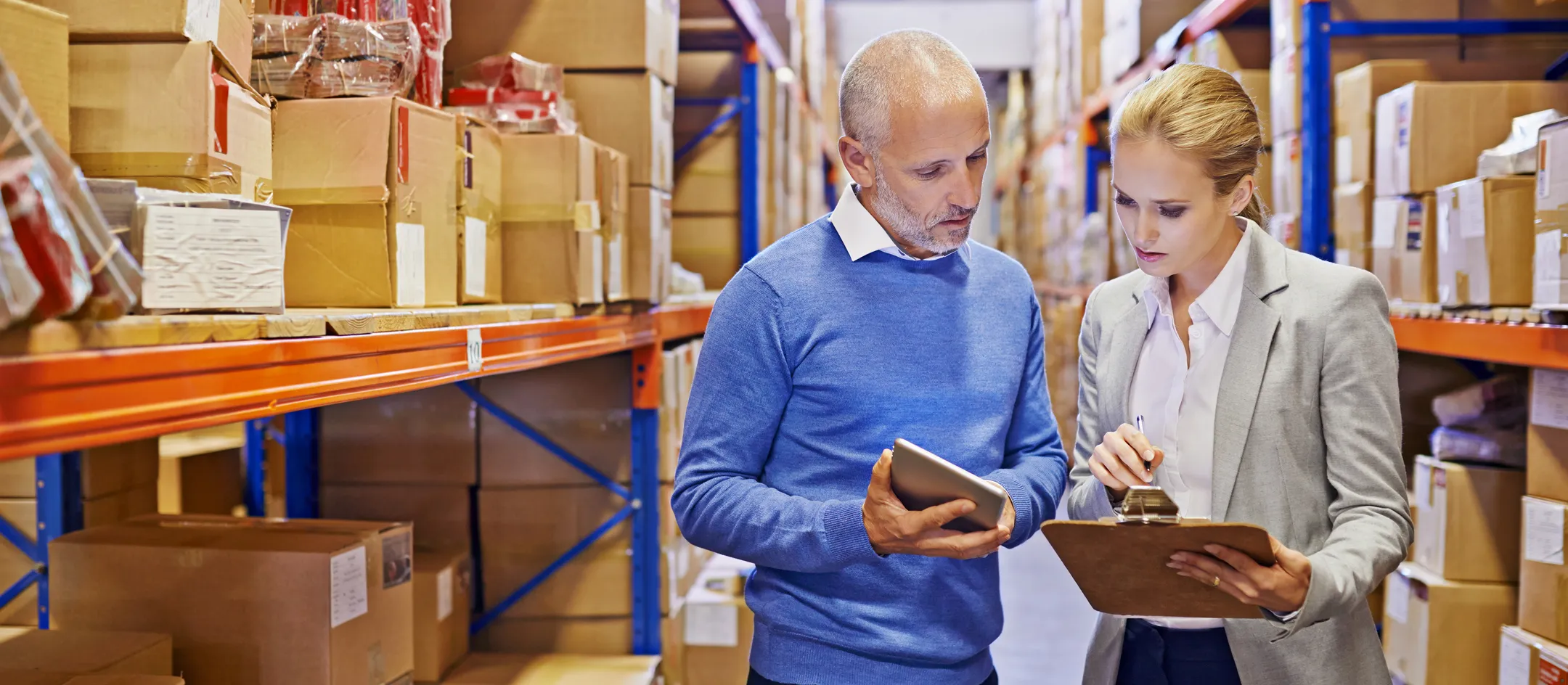 Two employees reviewing inventory on a tablet in a distribution warehouse