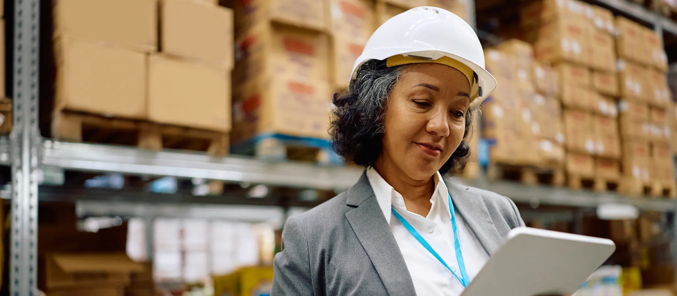 Worker in a hard hat using a tablet in a warehouse