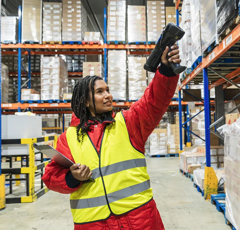 Warehouse worker in a hi-vis vest scanning stock with a handheld barcode scanner