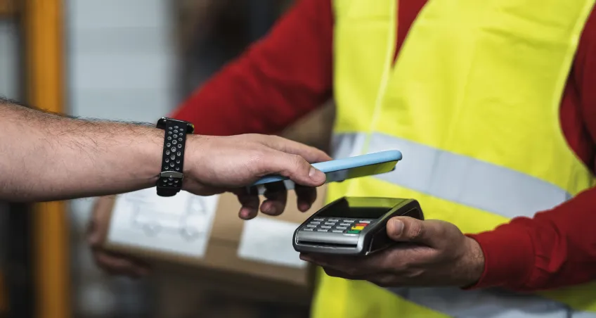 Contactless phone payment on a terminal held by a worker in hi-vis