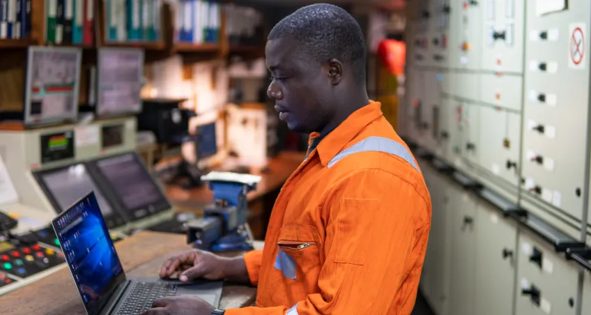 Worker using a laptop at an electrical control panel
