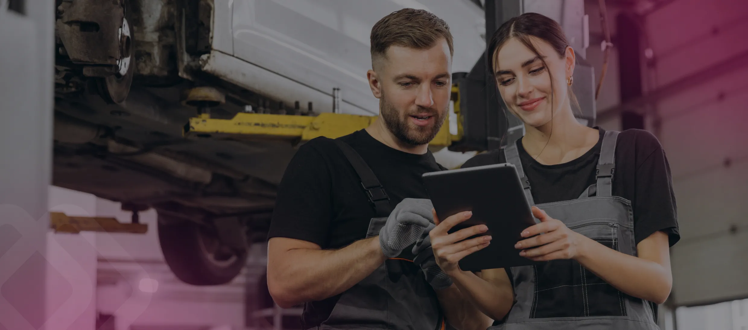 Two colleagues with a tablet at a car in a workshop