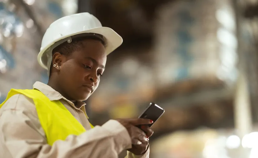 Worker in hi-vis using a phone in a warehouse