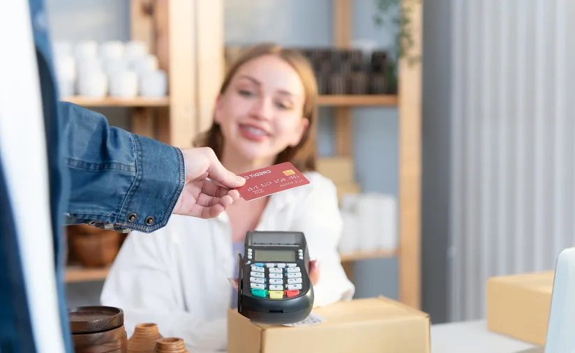 Customer paying by credit card on a card machine at a shop counter
