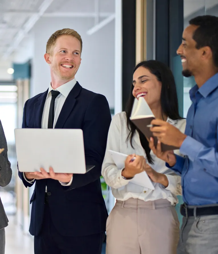 Smiling business colleagues using a laptop together in a modern office