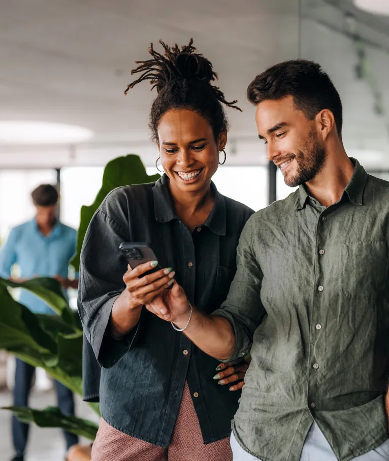 Two colleagues looking at a phone in an office