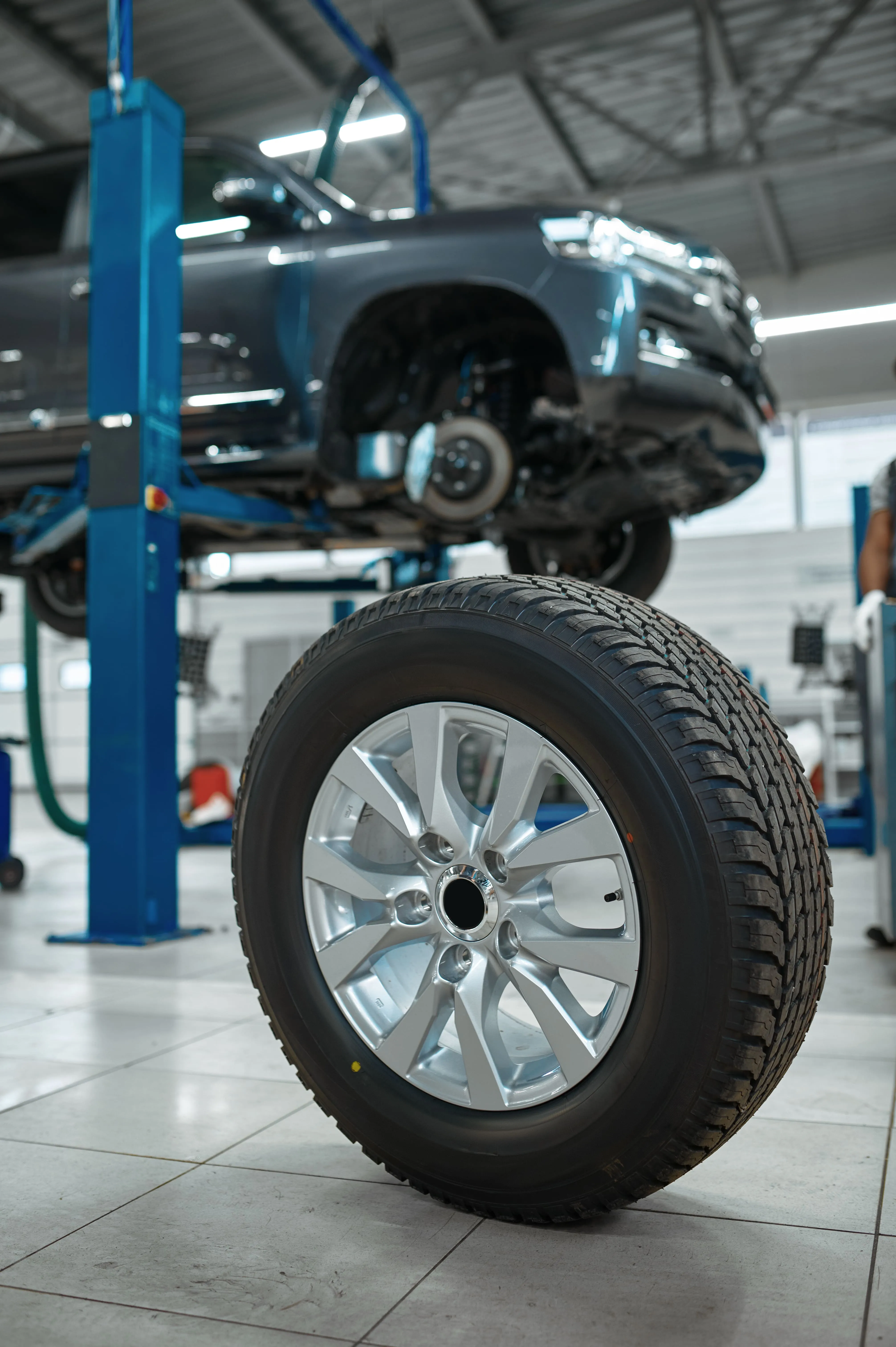 Pickup truck on a workshop lift beside a tyre