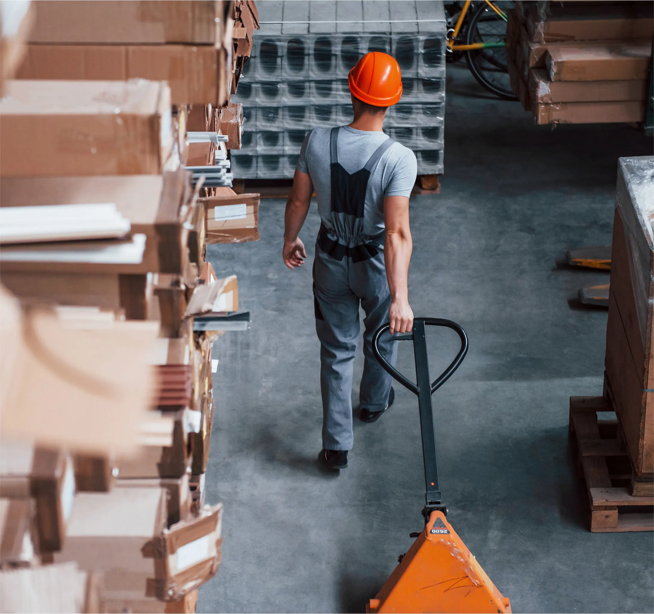 Worker in a hard hat moving a pallet truck in a timber warehouse