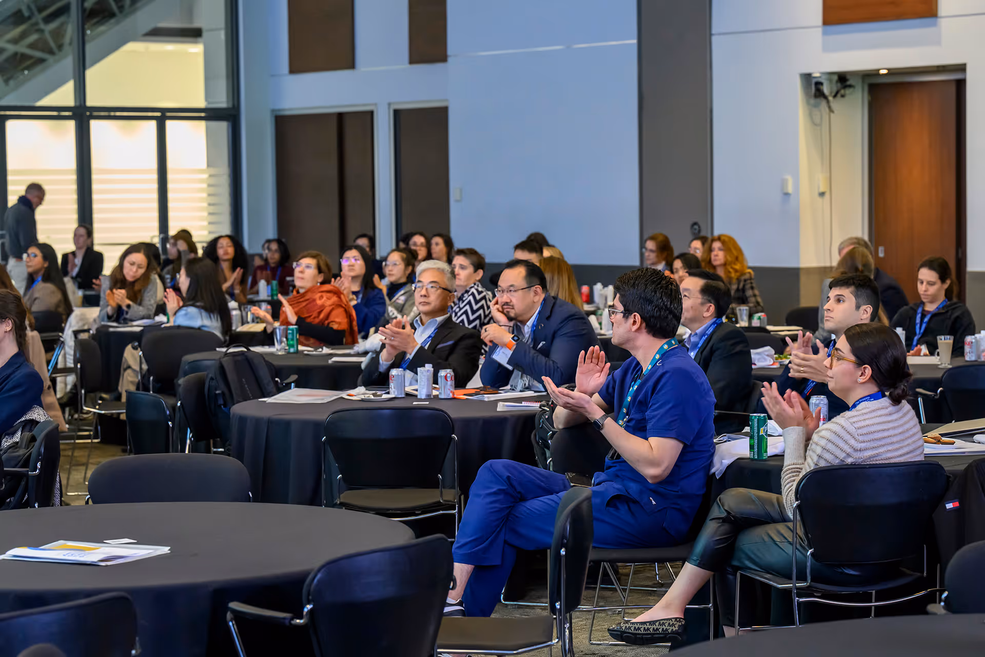 2024 Symposium's attendees sitting and applauding in a conference room.