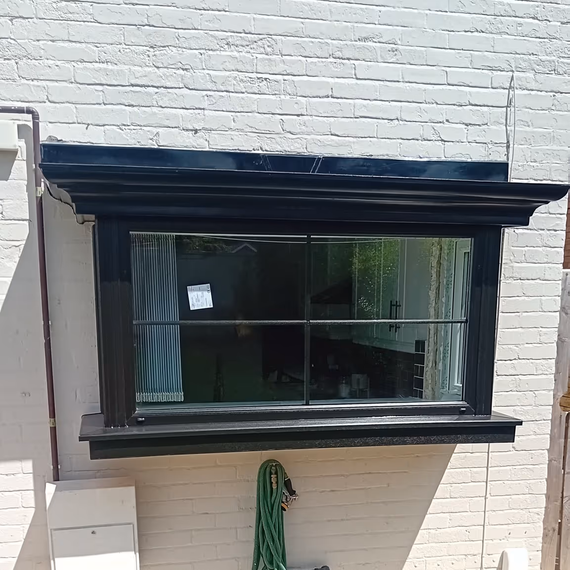 After image of Black replacement window fitted with modern glazing on a white brick house