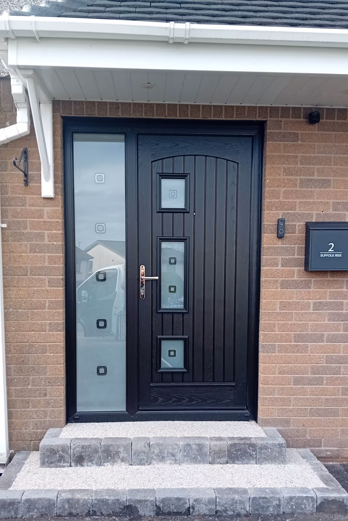 Black composite front door with frosted glass side panel fitted on a brick house